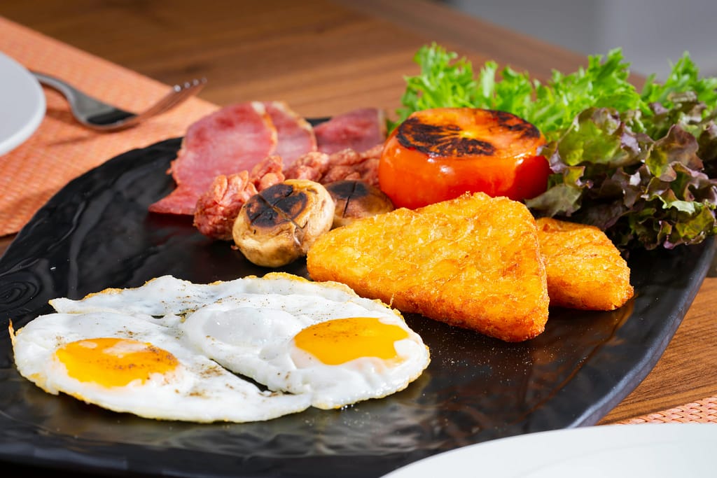 Traditional English breakfast with eggs, hash browns, bacon, and grilled vegetables at a top restaurant in Sotogrande