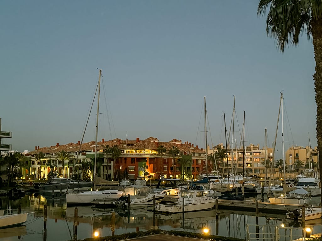 Sotogrande Marina at dusk with luxury yachts and waterfront residences reflecting on calm waters.