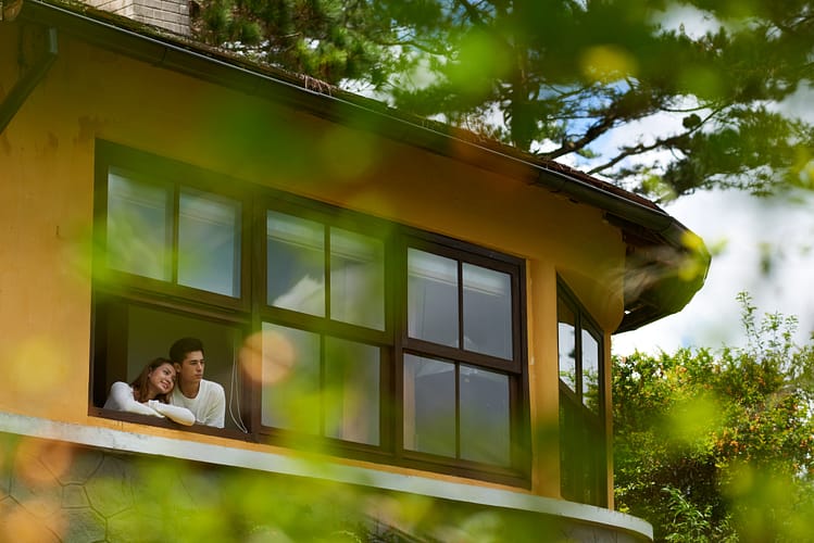 Couple enjoying the view from a modern window of a Sotogrande property surrounded by greenery